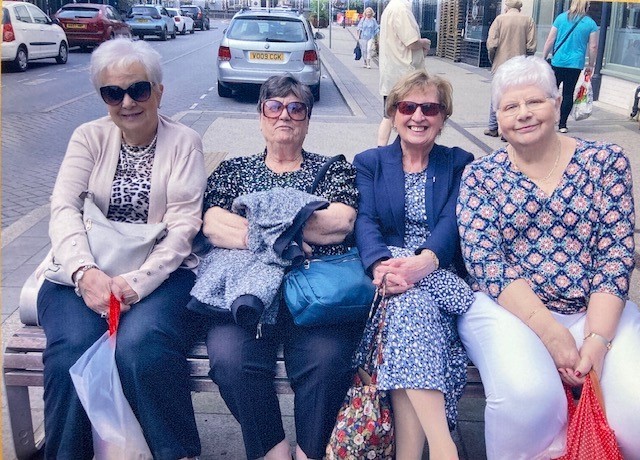 Four members of the rotary club sat on a bench in town